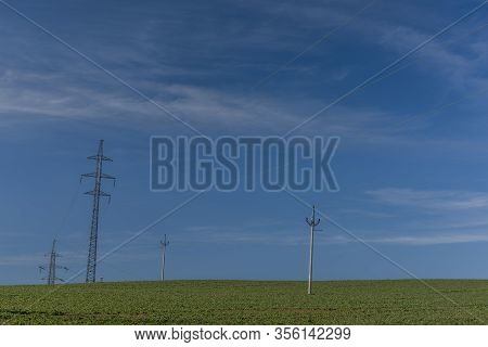 Hight Electric Wires And Poles On Green Spring Field With Blue Sky