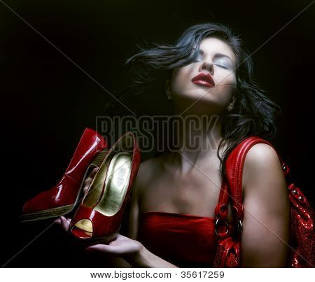 modello di moda con borsa rossa e scarpe rosse. su sfondo nero.