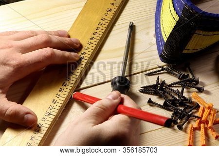 Different Tools On A Wooden Background. Carpenter Tools On A Table. Hand Holding Riler And Pencil.