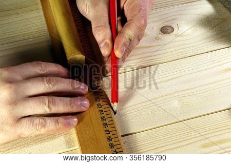 Different Tools On A Wooden Background. Carpenter Tools On A Table. Hand Holding Riler And Pencil.