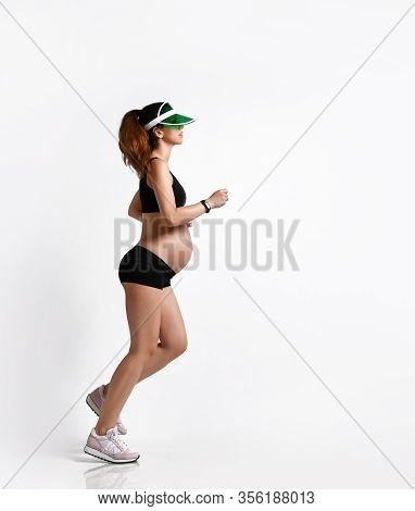 Pregnant Girl With Belly, In Green Sun Visor, Black Sport Shorts And Top, Pink Sneakers. She Is Jogg
