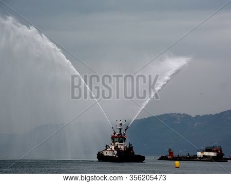 Trieste Italy 05 19 2019: Deneb Tug Boat In Trieste Italy Giving Farewell Salute With Fire Hoses Wit