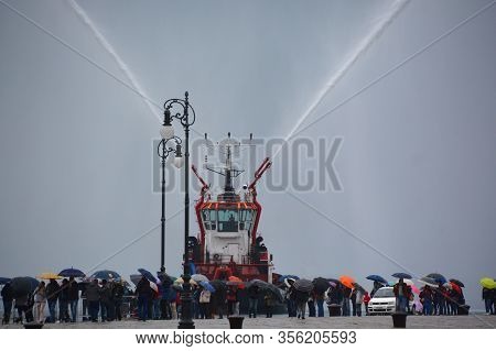 Trieste Italy 05 19 2019: Deneb Tug Boat In Trieste Italy Giving Farewell Salute With Fire Hoses Wit