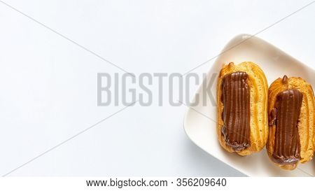 Part Custard Cakes With Chocolate Icing On A White Background. Copy Space