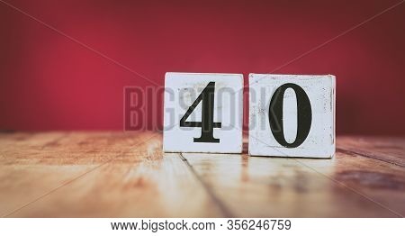 Number 40 On A Vintage Wooden Table And Dark Maroon Background - Retro Style White Blocks