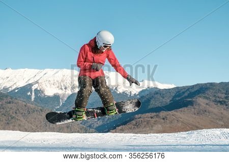 Pretty Young Woman On The Snowboard Jumping Over The Slope In Winter