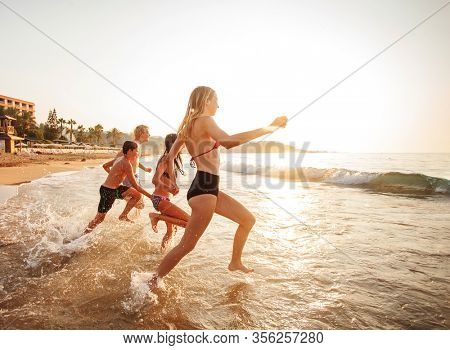 Happy young peaple having fun at beach on sunny day. Smiling teens on vacation