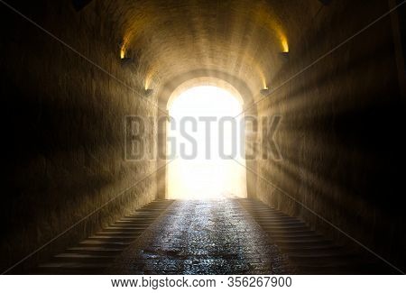 A Bright Yellow Glowing Light Breaking Through At The End Of A Dark Tunnel