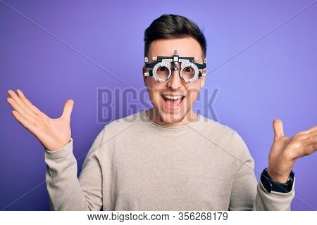 Young handsome caucasian man wearing optometrical glasses over purple background celebrating crazy and amazed for success with arms raised and open eyes screaming excited. Winner concept