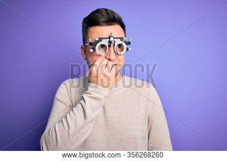 Young handsome caucasian man wearing optometrical glasses over purple background looking stressed and nervous with hands on mouth biting nails. Anxiety problem.