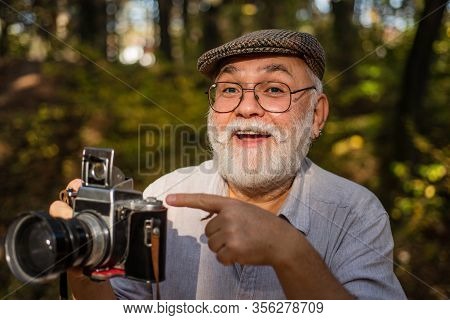 Look At This. Old Photographer Pointing At Retro Camera. Bearded Man Pointing Finger Outdoors. Point