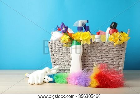 Wicker Basket With Spring Flowers And Cleaning Supplies On Wooden Table