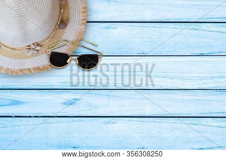 Summer Concept. Straw Hat And Sun Glasses On Blue Wooden Background. Top View With Copy Space.