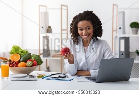 Attractive Woman Doctor Sitting At Dietologist Workplace In Front Of Laptop, Kindly Recommending Eat