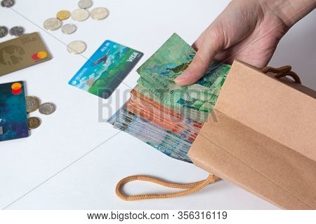 Person Pulls The Money Out Of The Bag. Tenge, Kazakhstan, Banknote. Kraft Package With Paper Currenc