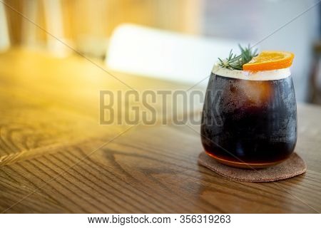 Glass Of Espresso Shot Mixed With Orange Juice On Wood Table. Refreshing Summer Drink Concept