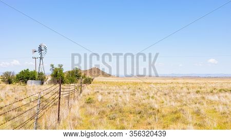 Windmill On A Farm In Rural Grassland Area Of South Africa