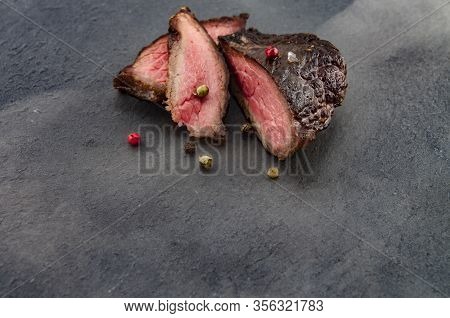 Freshly Grilled Steak With Colored Pepper On A Slate Board Wrapped In Smoke. Beef As A Main Lifestyl