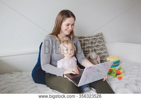 Young Caucasian Mother With Baby Working On Laptop From Home. Workplace Of Freelance Woman Student W
