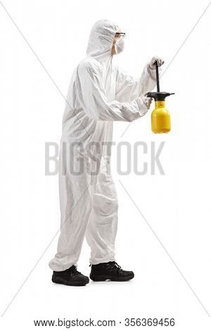 Full length profile shot of a man in a hazmat suit spraing with a disinfectant isolated on white background