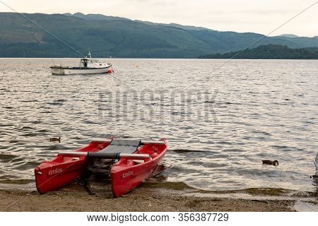 Luss, Scotland - August 1, 2019: A Red Katakanu Boat At Loch Lomond Lake In Scotland To Be Hired By 