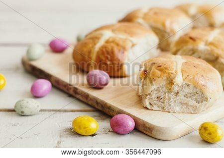 Hot Cross Buns Served On A Wooden Board And Small Chocolate Eggs. Easter Treats. Festive Season