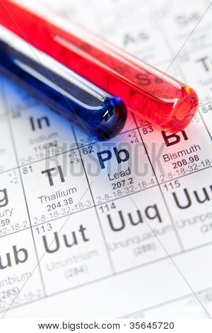 zwei Reagenzgläser mit farbigen Reagenzien auf das Periodensystem, liegend hautnah Schuss