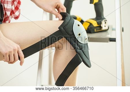 Unrecognizable Woman Wearing And Adjusting Her Safety Knee Protectors Pads. Safe Workwear During Con