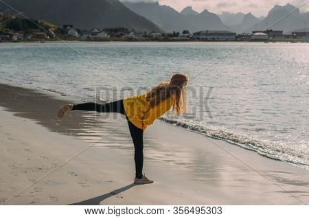 Girl In Yellow Jacket On The White Sand  Beach In Ramberg On Lofoten Islands, Norway