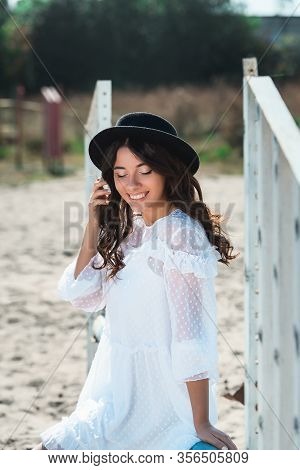 Beautiful Sexy Girl Posing On The Horizontal Crosspiece On A Horse Epodrom. Female Wearing White Dre