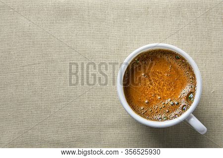 White Ceramic Cup With Freshly Brewed Hot Coffee With Crema On Linen Kitchen Table Cloth Top View. M
