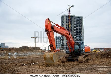 Excavator Working At Construction Site On Earthworks. Backhoe Digs Ground For The Foundation And For