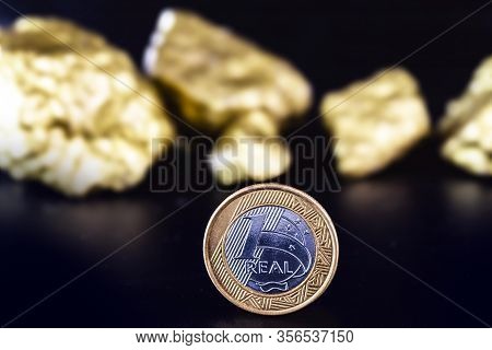 One Real Coin On Isolated Black Background With Gold Nuggets. Concept Of Appreciation Of The Brazili
