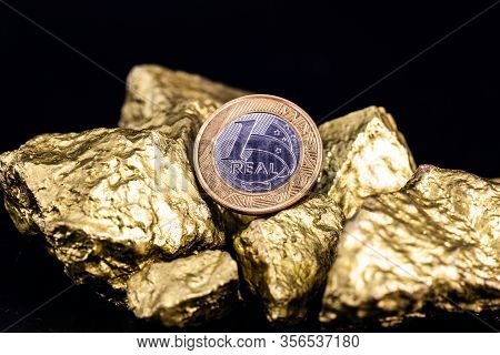 One Real Coin On Isolated Black Background With Gold Nuggets. Concept Of Appreciation Of The Brazili