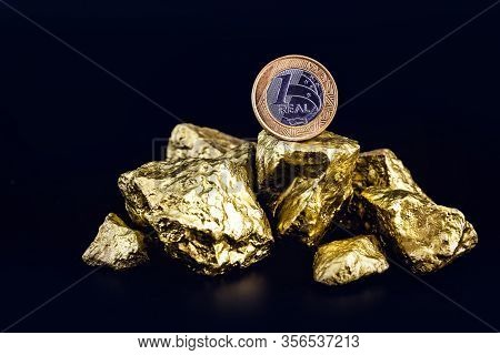 One Real Coin On Isolated Black Background With Gold Nuggets. Concept Of Appreciation Of The Brazili