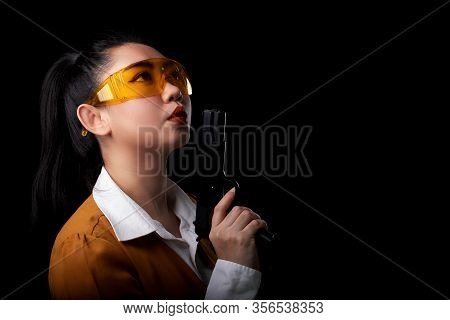 Portrait Beautiful Asea Woman Wearing A Yellow Suit One Hand Holding Pistol Gun At The Black Backgro