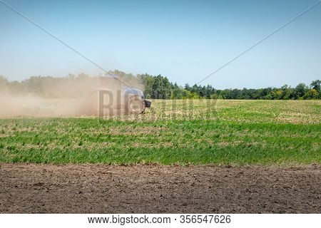 Blue Modern Tractor Covered With Earth Dust Plowing Agricultural Field At Farm On Bright Sunny Day. 