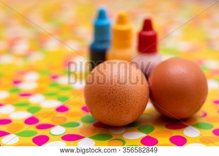 Two Chicken Eggs On A Multi Colored Vibrant Custom Background. Red Yellow And Blue Paint In The Back