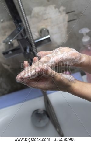 A Child Washes His Hands In Front Of A Faucet With Water In The Bathroom. Close-up.