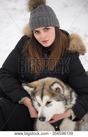 Beautiful Girl In Winter Forest With Dog. Play With The Dog Siberian Husky.
