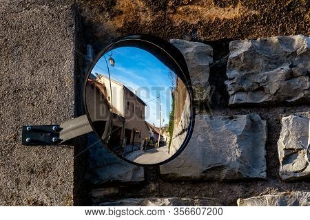 The View Of A Narrow French Village Street Reflected In A Road Mirror On A Sunny Day