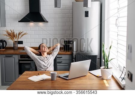 Home Office, Distant Work, Freelancer. Young Woman Takes A Break, Resting Leaning Back In A Chair In