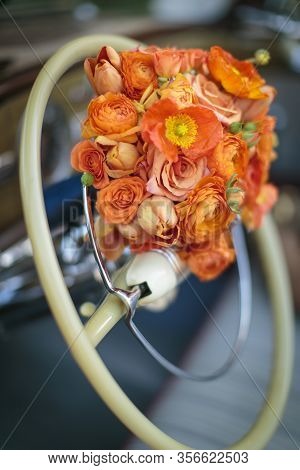 Sterring Wheel Of A Vintage Car With A Wedding Bouquet In Orange Colors