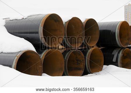 Snow Lies On Pipes. Large Diameter Pipes Are Stacked In Row.