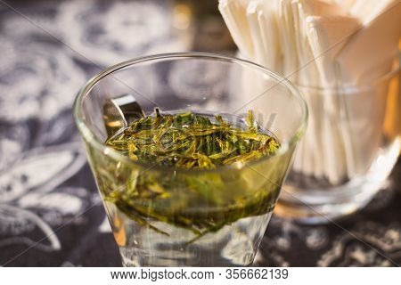 Longjing Dragon Well Tea Leaves On A Small Glass With Warm Water