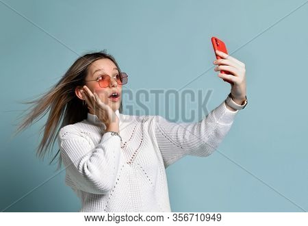 Blonde Teenager In Orange Sunglasses, Smart Watch, Bracelet And Sweater. She Is Taking A Selfie, Loo