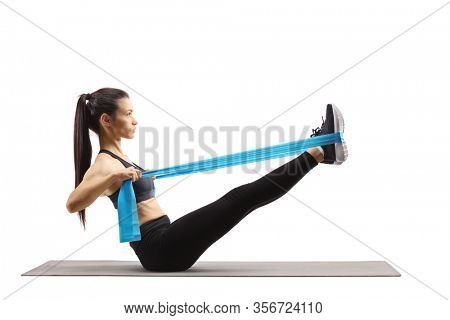 Young woman exercising on a mat and stretching legs with an elsatic band isolated on white background