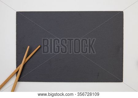 Rectangular Slate Plate With Chopsticks For Sushi On The White Table. Food Design