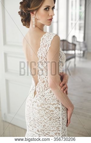 Beautiful Bride Posing In Wedding Dress In A White Photo Studio. Mirror. Sofa. Bouquet. The Door. Ch