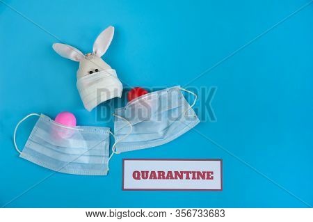 The Concept Of Quarantine At Easter Time. Easter Bunny And Painted Eggs In A Medical Mask, A Message